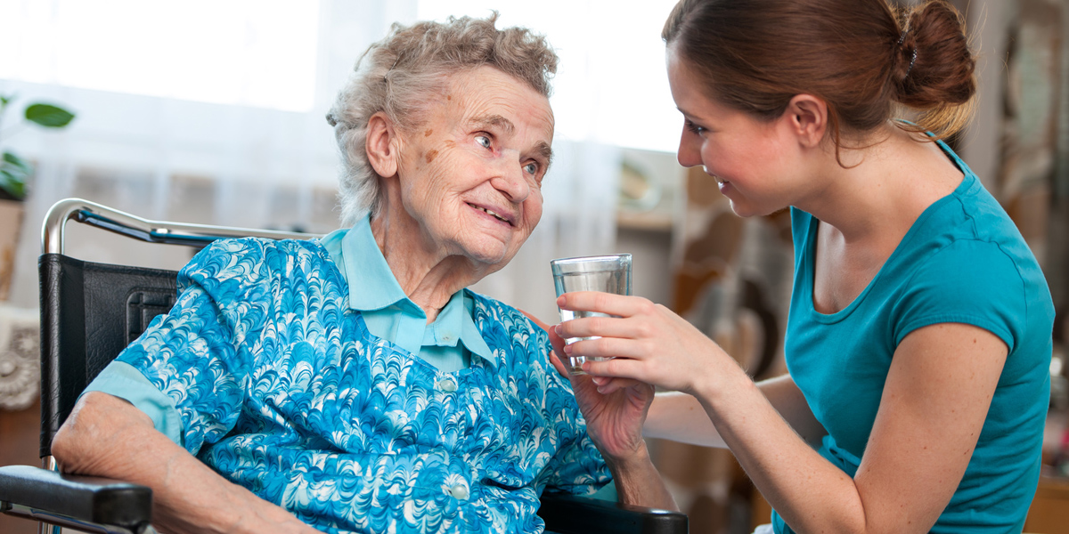 Bild: Eine ältere Frau bekommt von einer Pflegerin ein Glas Wasser,  Foto: © Alexander Raths / Fotolia
